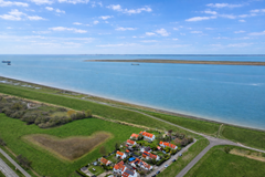 Kustdorp met rode daken en zee.png